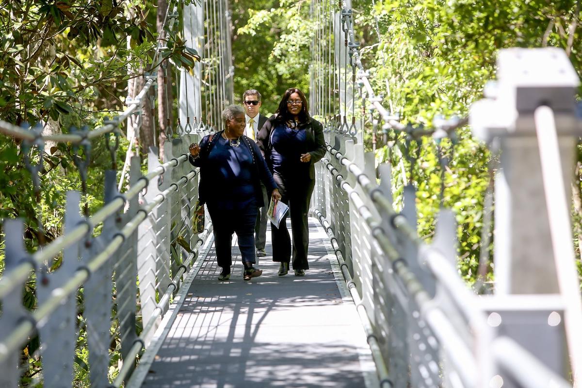 Visitors walk over a suspension bridge that links the two campuses of the new University of Southern Mississippi’s Marine Education Center at the Gulf Coast Research Laboratory Cedar Point Site on April 16, 2018.