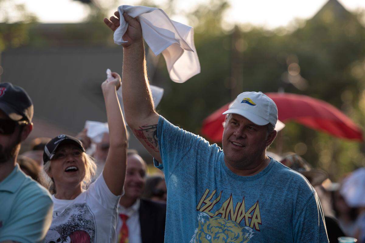 Parade goers wave handkerchiefs during a second-line celebration for the life of Carl, a beloved rooster who was killed in April, in Ocean Springs on Tuesday, May 10, 2022.