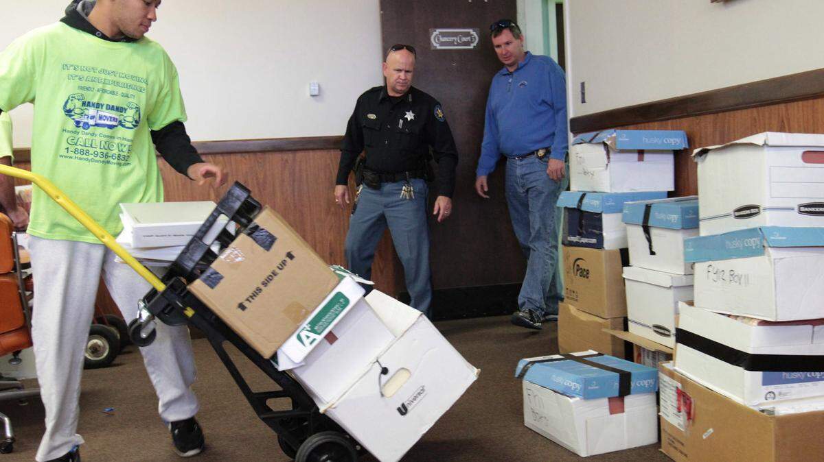 JOHN FITZHUGH/SUN HERALD 
 State auditor's office special agent Chris Lott, right, and Harrison County Sheriff's Deputy Allan Cramer watch as DMR records are delivered to the Harrison County courthouse in Gulfport on Friday Dec. 27, 2013. Chancery Judge Jennifer Schloegel had declared the records public, but the state Court of Appeals reversed her ruling Tuesday.