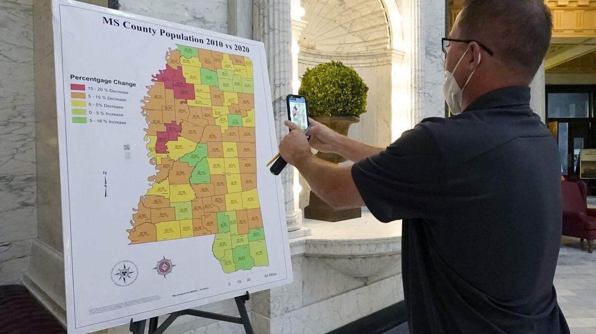 A visitor to the Mississippi Capitol in Jackson, uses his cell phone to photograph a graphic of the state that depicts census growth or loss in each county over a 10-year period in Jackson, Miss., Thursday, Aug. 26, 2021.