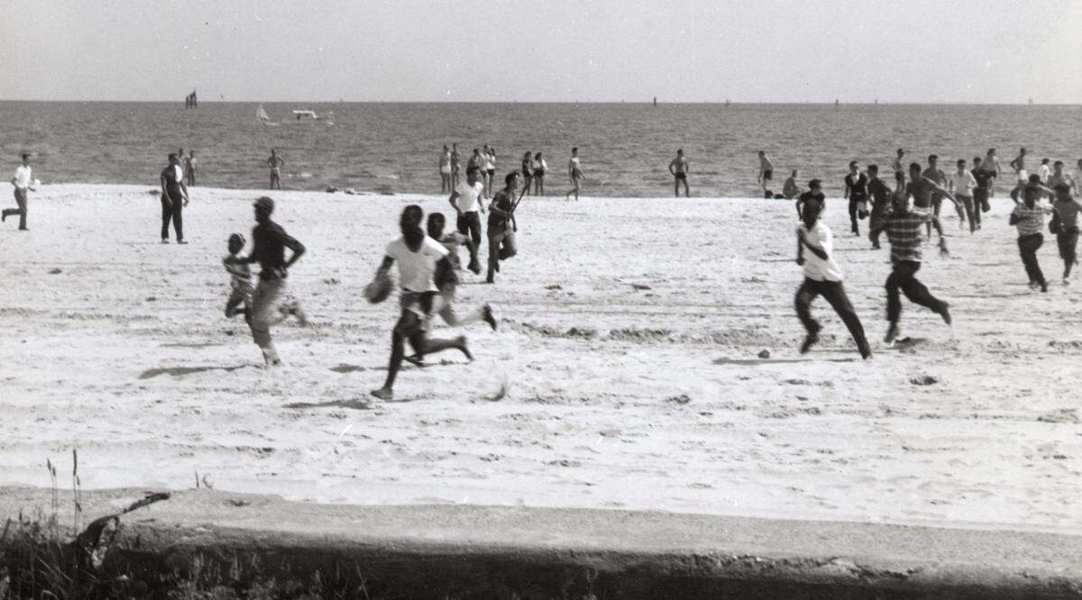 A white mob chases wade-in participants off the beach in Biloxi on April 24, 1960. Clemon Perry Jimerson Sr., then 14, is pictured in the top right corner in a white swimsuit.