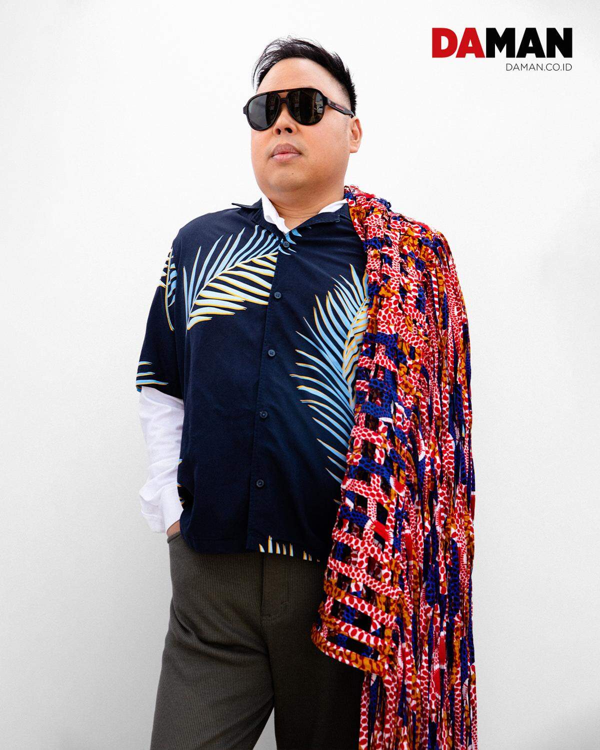 On his shoulder, actor Nico Santos drapes a colorful shawl made of a basket weave of African prints featuring a red and white spotted print, blue and black cheetah print and orange and red African design. 