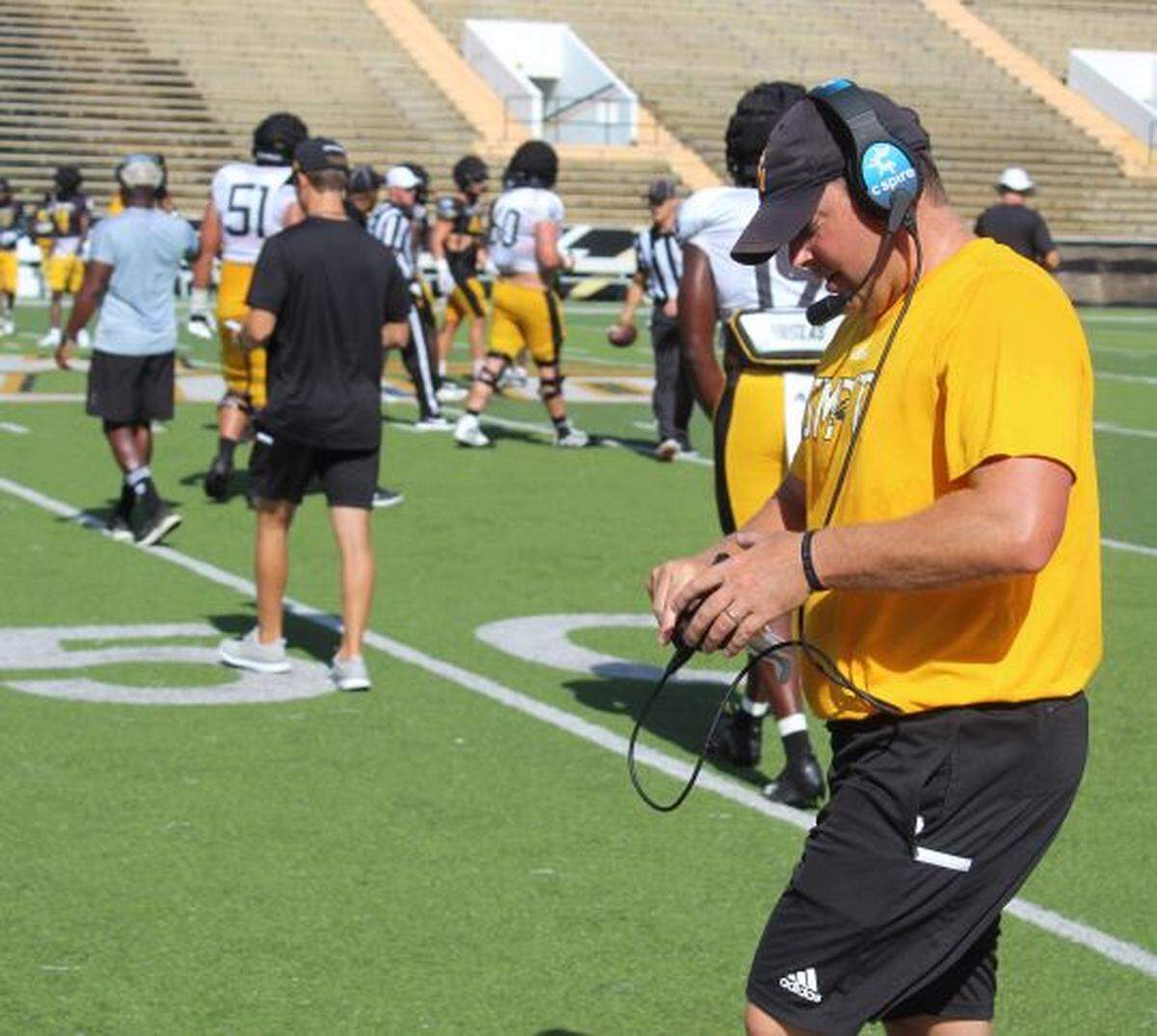 Head football coach Will Hall adjusts his mic pack during the final preseason scrimmage with the Southern Miss team on Saturday, Aug. 21, 2021.