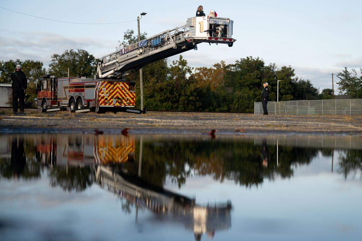 A firetruck is reflected in a puddle during the Champions Christmas Parade in Gulfport on Monday, Dec. 8, 2025.