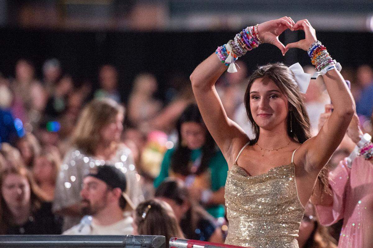 A fan makes a heart with her hands for a photo before the start of Taylor Swift’s The Eras Tour at the Cesars Superdome in New Orleans on Friday, Oct. 25, 2024.