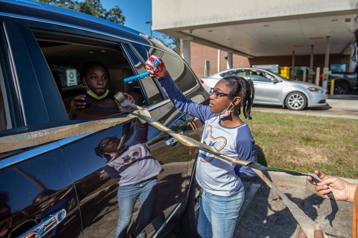 Saniyah Curry, 9, hands a kazoo to her sister Mashiyah Curry, 11, as they prepare their car for a retirement parade for their church pastor, Seymour Venson Adolph, Jr., in Gulfport on Saturday, Dec. 4, 2021. Mashiyah reflected on Pastor Adolph’s tenure at Handsboro Baptist Church, saying that he was very patient with the children of the church and remembered their birthdays and other details about them.