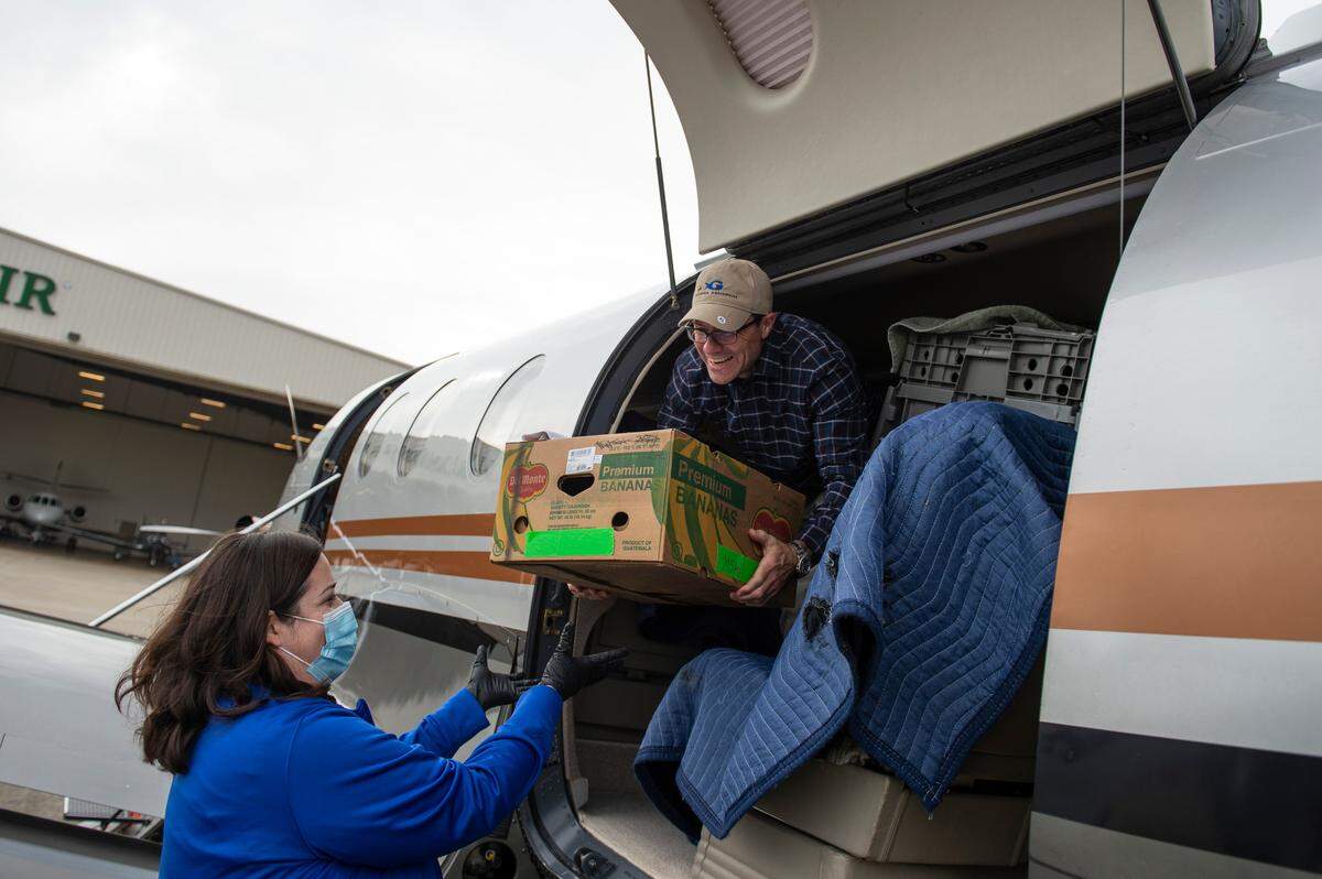 Steve Bernstein, right, a volunteer pilot for Turtles Fly Too, a non-profit that helps transport endangered species, hands Dr. Alexa Delaune, Vice President of veterinary services at the Mississippi Aquarium, a banana box containing a Kemp’s Ridley sea turtle from an airplane at the Gulfport Airport in Gulfport on Monday, Dec. 20, 2021.