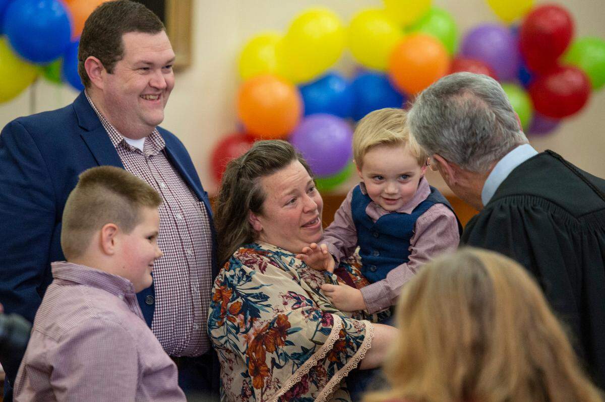 Donald “Heath” Shaw and Judy Shaw hold up their now legal son Colton, 3, to the judge while Micheal, 8, whose adoption was also finalized, looks on during adoption day on Thursday, March 10, 2022.