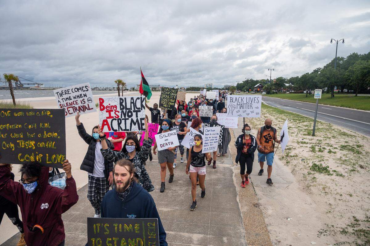 Protesters march down Highway 90 Saturday June 6, 2020 as they chant “Black Lives Matter” and hold up signs to passing cars.