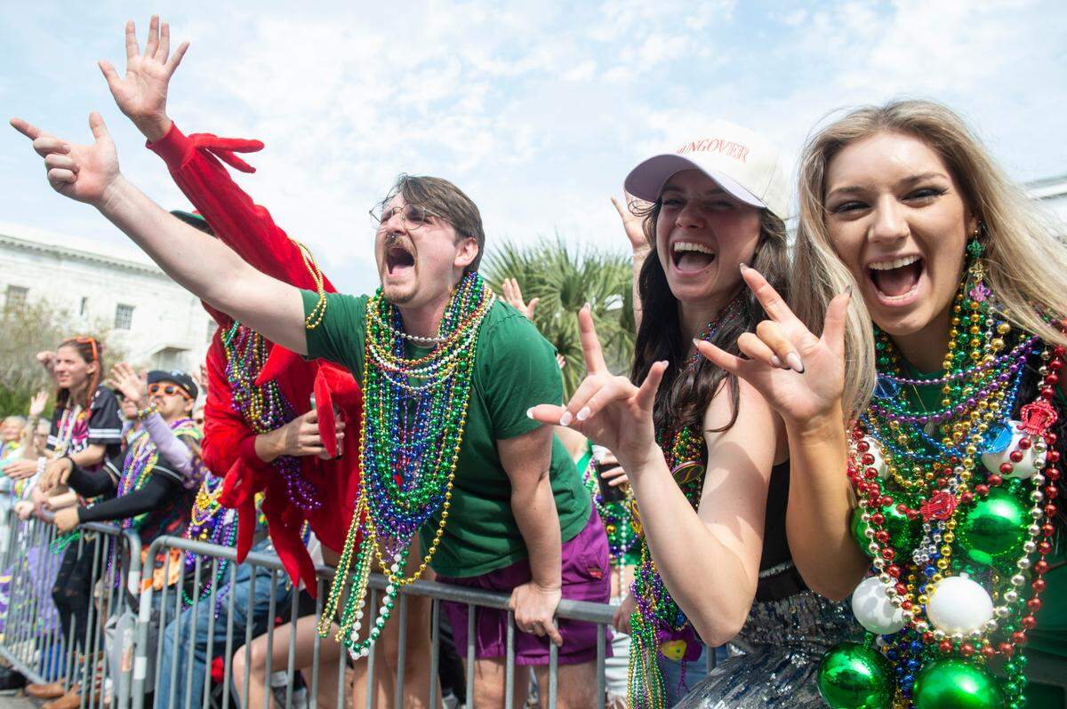 Parade watchers cheer for beads and other throws during the Gulf Coast Carnival Association Mardi Gras parade in Biloxi on Tuesday, March 4, 2025.