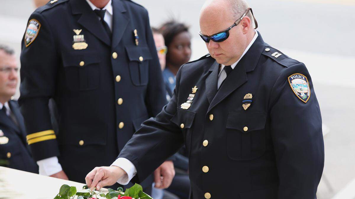 AMANDA McCOY/SUN HERALD 
 Captain Neal Stachura places a rose at the foot of a monument honoring the eight Gulfport Police Department members who have died in the line of duty in last year's memorial ceremonies. Friday's 9 a.m. service has been moved inside the police department's press room due to the threat of rain.