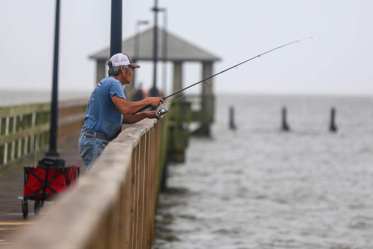 A fisherman tries his luck off the side of the Biloxi Lighthouse Pier as waters begin to get choppy from Hurricane Zeta Wednesday morning, Oct. 28, 2020.