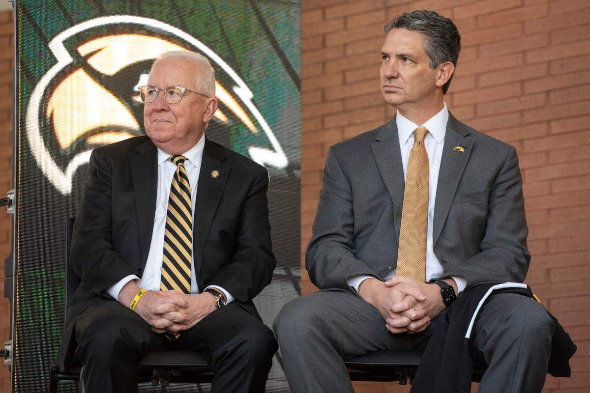 University of Southern Mississippi President Joseph Paul, left, and Southern Miss Athletic Director Jeremy McClain listen as new head football coach Charles Huff makes a speech during a public welcome celebration for Huff at The Rock in Hattiesburg on Thursday, Dec. 12, 2024.
