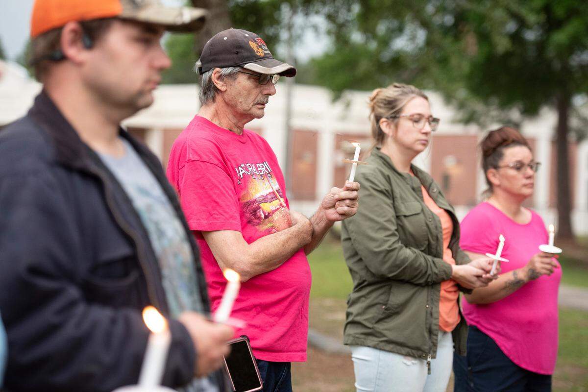 Community members hold candles and pray during a candlelight vigil in remembrance of Gracelynn Vick at Saucier Park on Tuesday, April 22, 2025.