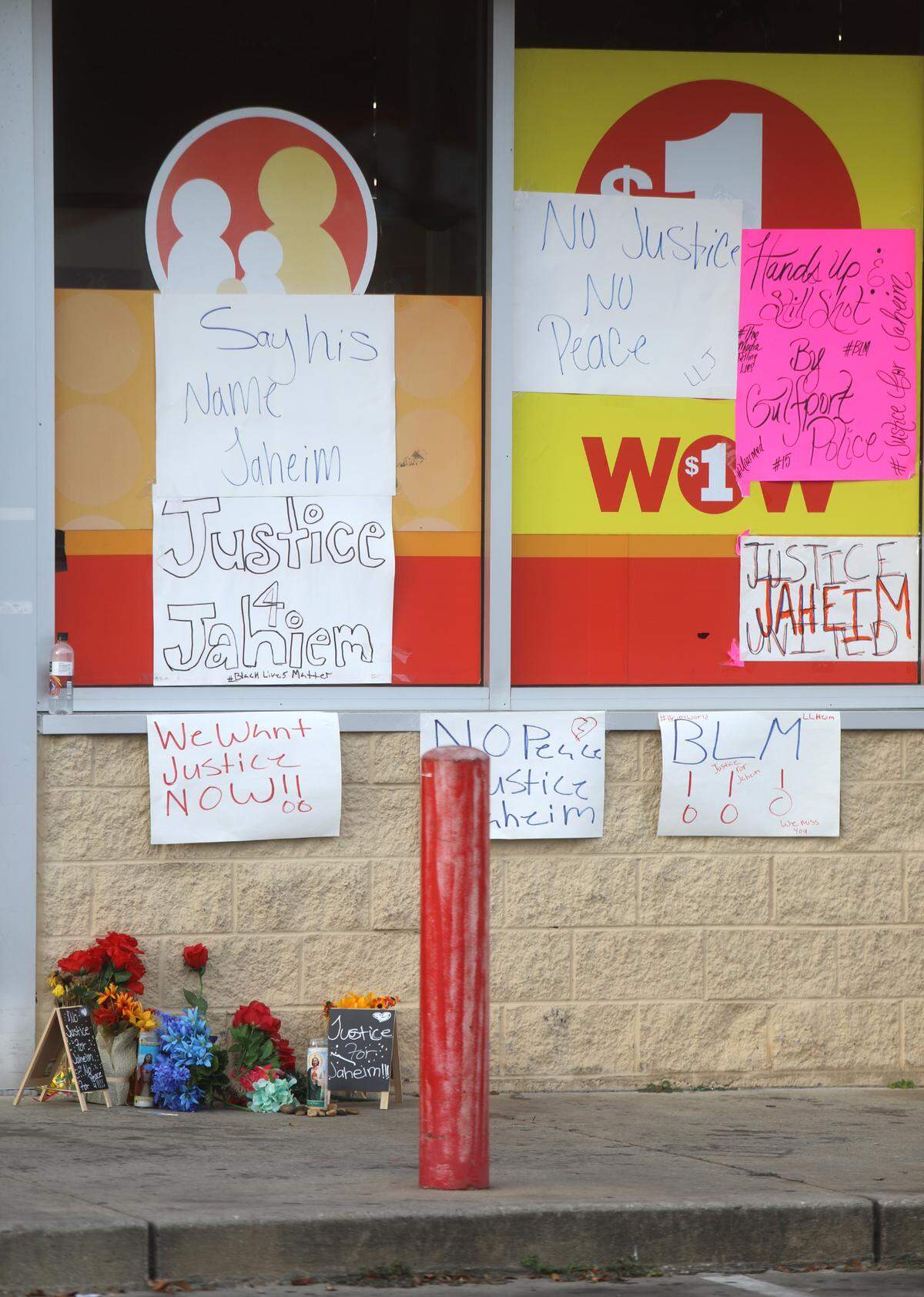 A memorial of flowers and signs that demand justice for Jaheim McMillan sits near the entrance of Family Dollar on Pass Road in Gulfport. The 15-year-old died after being shot in the head by a police officer.