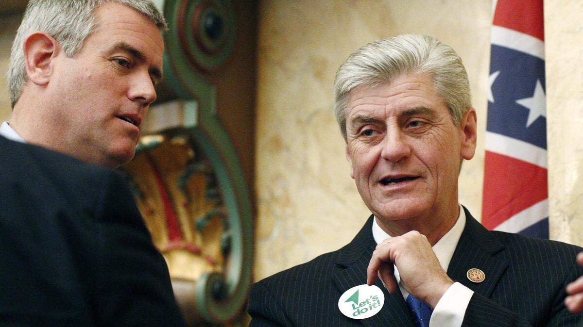 Sporting a "Let's Do It" sticker, Republican Gov. Phil Bryant, right and House Speaker Philip Gunn, R-Clinton, discuss the passage of an economic development incentive bill for a tire plant in western Hinds County and a shipyard in Gulfport, Thursday, Feb. 4, 2016, at the Capitol in Jackson, Miss. Gov. Bryant set Thursday's special session for the two economic development projects that could create 3,500 jobs. The bill passed the House and was sent to the Senate for consideration. (AP Photo/Rogelio V. Solis)