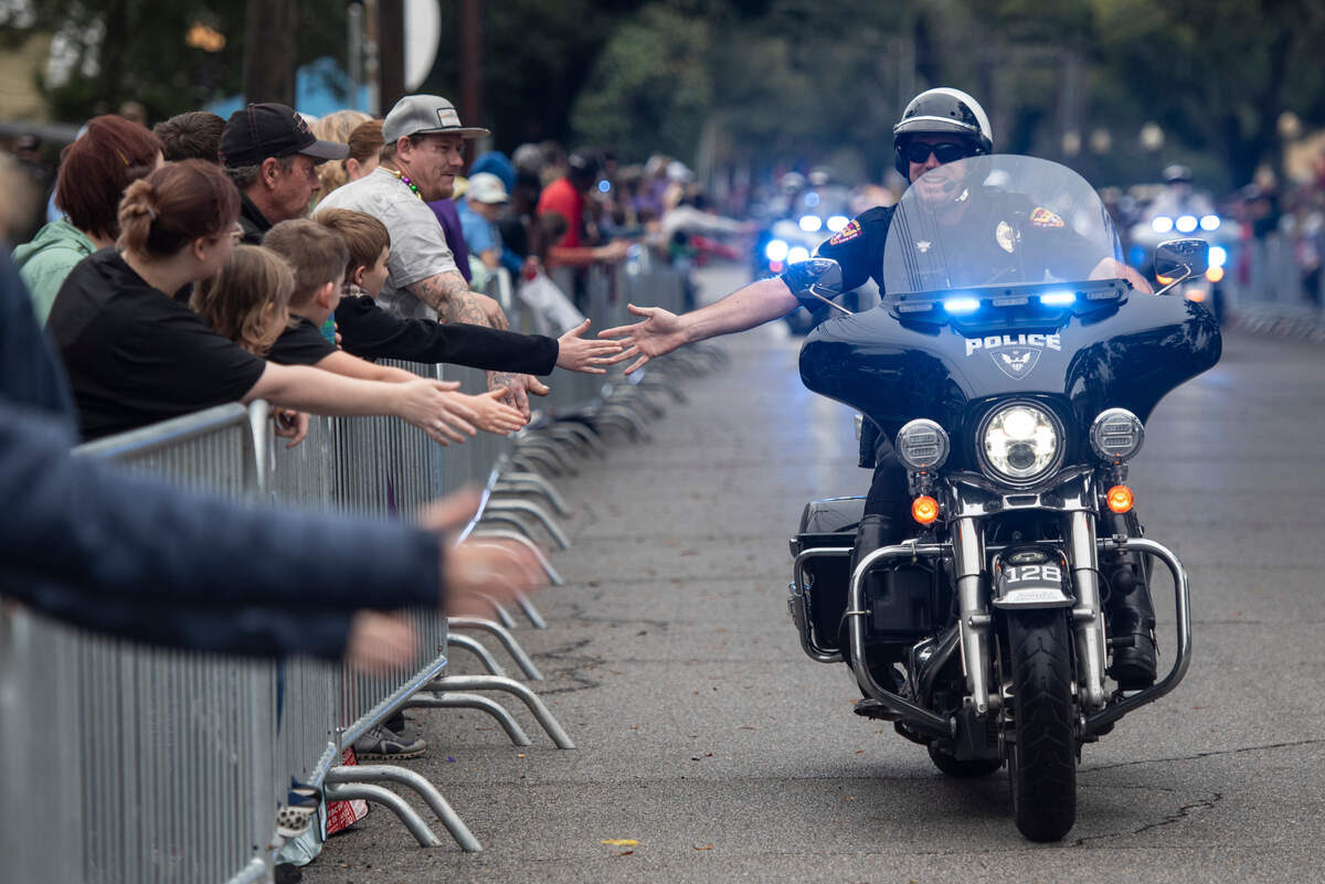 A Pascagoula police officer high-fives attendees before the start of The Ocean Springs Elks Carnival Parade in downtown Ocean Springs on Saturday, Jan. 27, 2024.