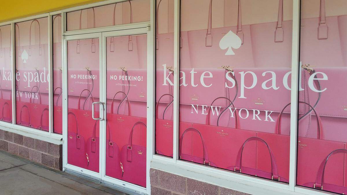 “No peeking” signs stretch across the windows of the Kate Spade New York store at Gulfport Premium Outlets. The store will open Friday.