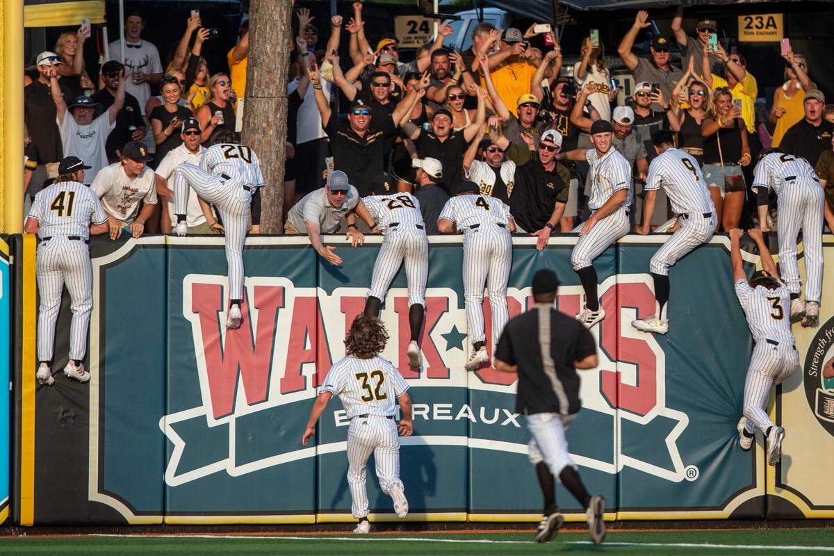 Southern Miss players climb over the right field wall after winning the Hattiesburg Regional on Monday, June 6, 2022.