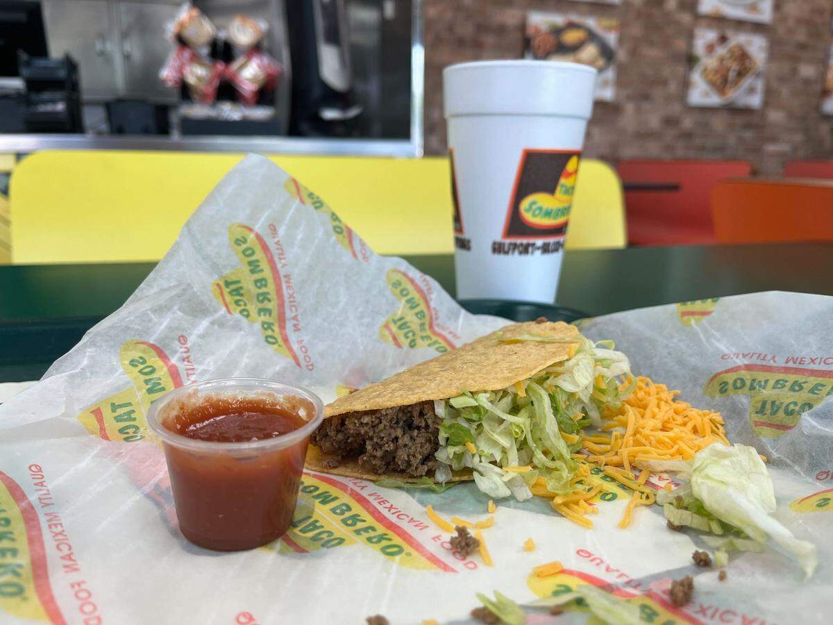 A hard shell beef taco rests beside a cup of Taco Sombrero’s signature hot sauce inside the Gulfport restaurant.