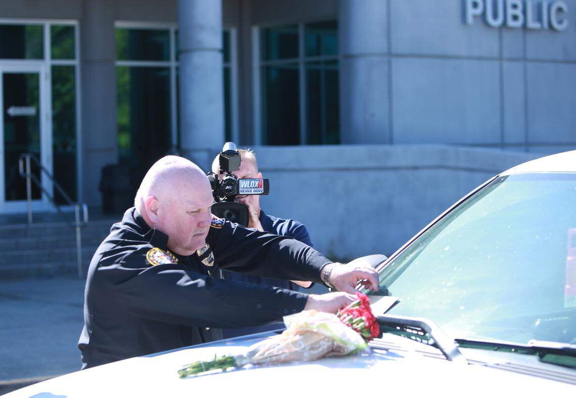 Biloxi Police Chief John Miller places flowers and a card on the police SUV of officer Robert McKeithen, killed in the line of duty on Sunday, May 5, 2019, outside the Biloxi Police Department. A manhunt is underway to find the suspect, who shot McKeithen multiple times, police say.