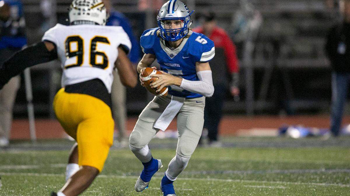 Ocean Springs quarterback Bray Hubbard dodges Oak Grove’s La’darrian Caldwell at Greyhound Stadium in Ocean Springs on Friday, Nov. 19, 2021.