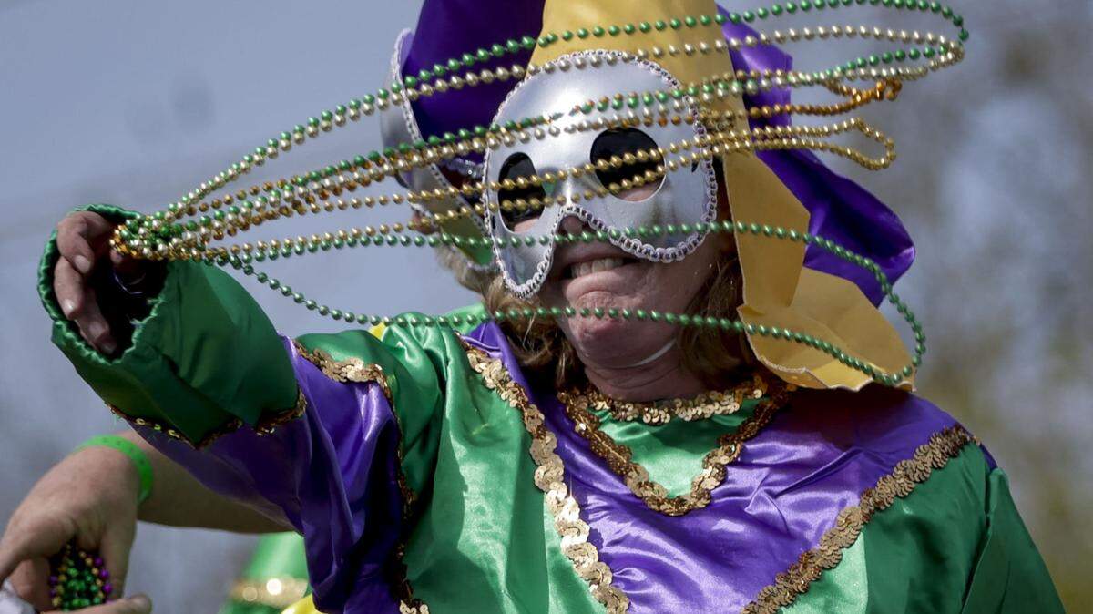A rider tosses beads as the Krewe of Argus rolls to the theme ‘Argus is Golden,’ during its 50th anniversary Tuesday, Feb. 21, 2023, in Metairie, Louisiana.