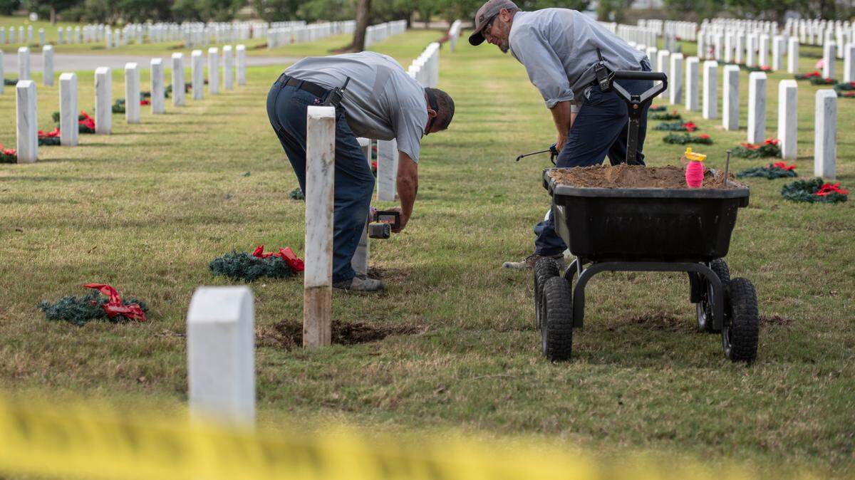 Workers fix headstones at Biloxi National Cemetery in Biloxi on Monday, Dec. 4, 2023, after a driver of a pickup truck ran them over on Sunday.