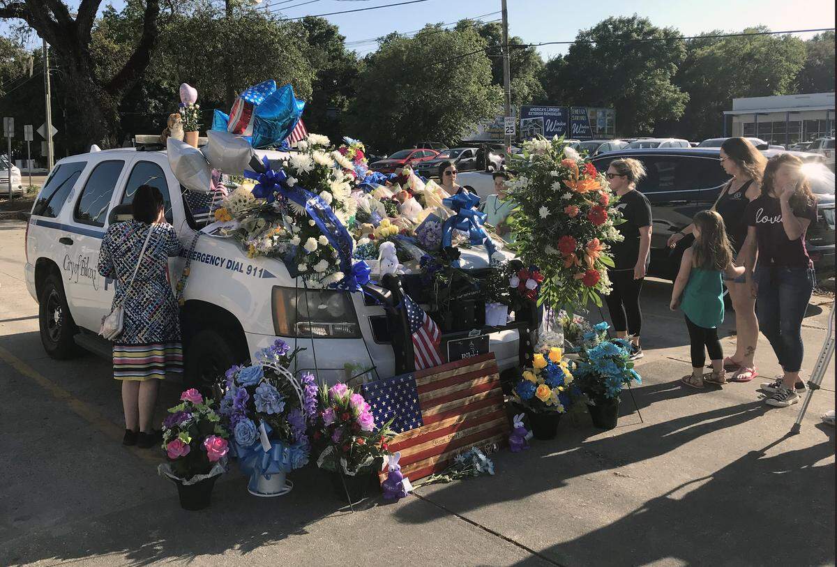 Residents mourn the death of police officer Robert McKeithen at a memorial on his patrol car in the Biloxi Police Department parking lot on Monday, May 6, 2019.