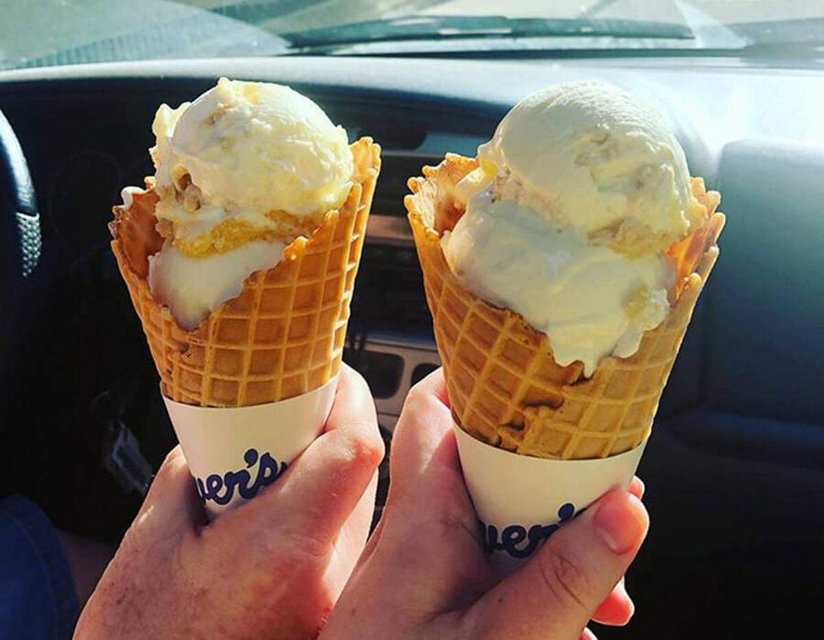 Picture of two hands holding frozen custard waffle cones in car.