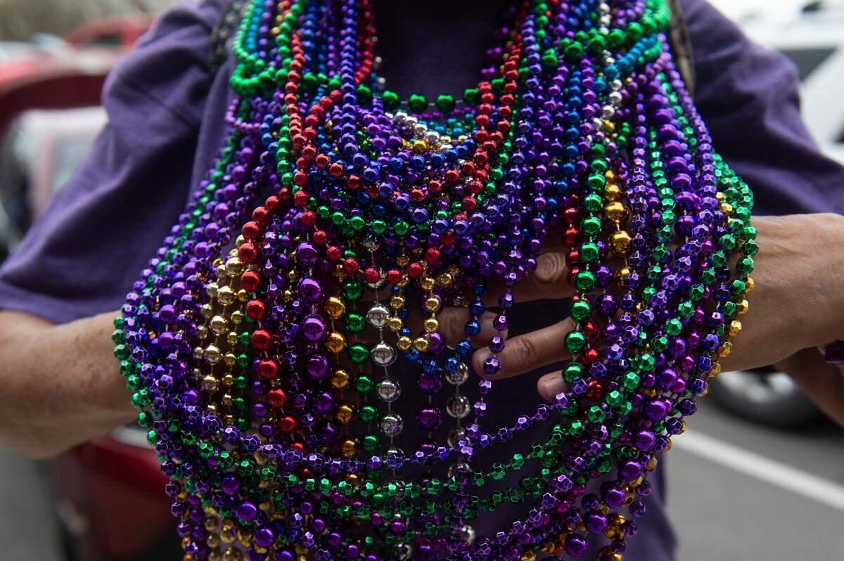 A paradegoer shows off their beads during the Krewe of Gemini parade in downtown Gulfport on Saturday, Feb. 10, 2024.