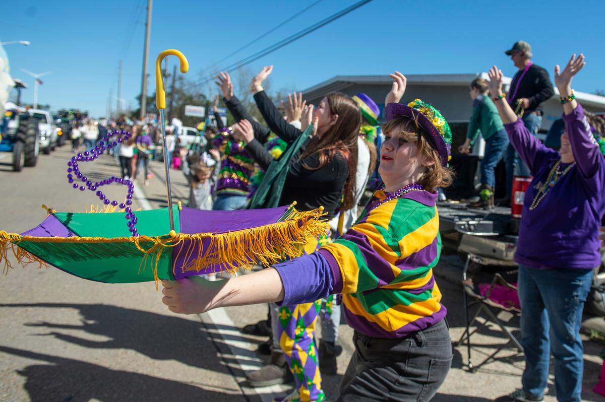 A parade-goer catches beads in an umbrella during the Krewe of Nereids Mardi Gras parade on Highway 90 in Bay St. Louis on Sunday, Feb. 12, 2023.