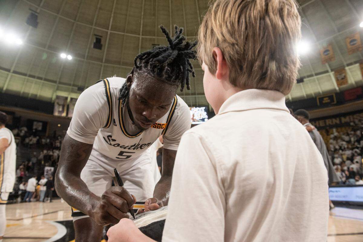 Southern Miss’s DeAndre Pinckney signs an autograph for a young fan after beating Louisiana-Lafayette at Reed Green Coliseum on Thursday, Feb. 9, 2023.