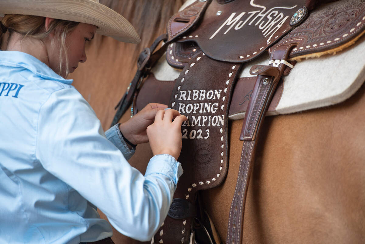 Kinsley McBride fixes a saddle she won in competition as she prepares her horse Jet for practice at the Harrison County Fairgrounds on Thursday, June 13, 2024.