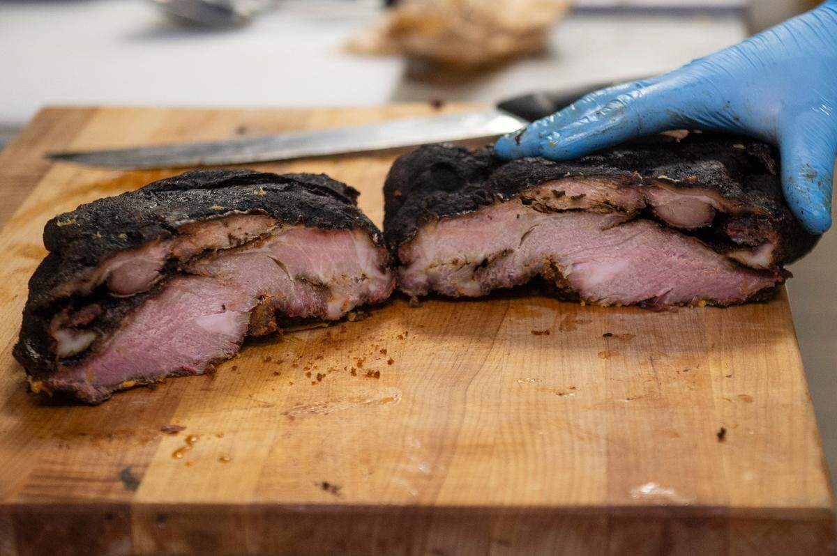 Joseph Mason, owner of 4 Bulls Farm to Table restaurant and the adjacent butcher shop, shows off the pulled pork Boston butt before it is separated as he works in the kitchen of the restaurant in Ocean Springs on Monday, Jan. 6, 2025.