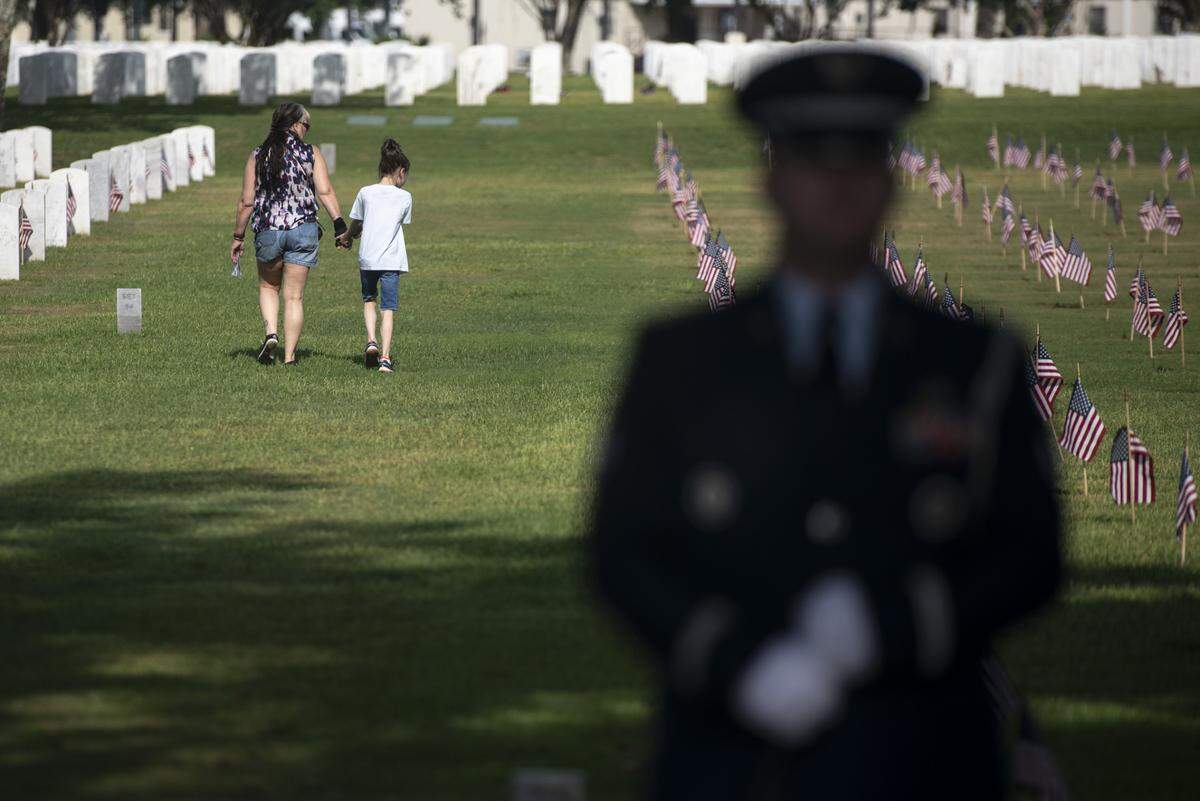 Families walk among the headstones at Biloxi National Cemetery in Biloxi during a Memorial Day ceremony on Monday, May 26, 2025.