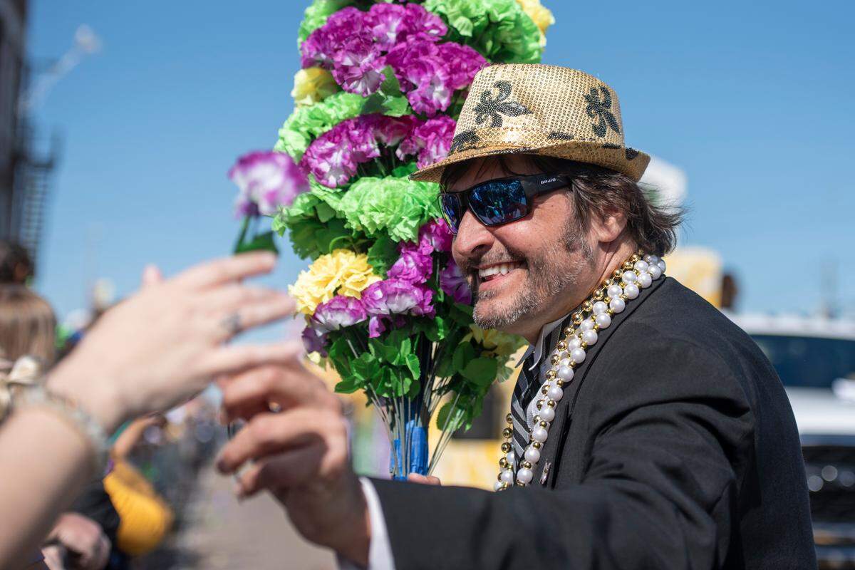 A member of the Ole Biloxi Marching Club hands out a flower during the Gulf Coast Carnival Association’s Mardi Gras parade in Biloxi on Tuesday, Feb. 13, 2024.