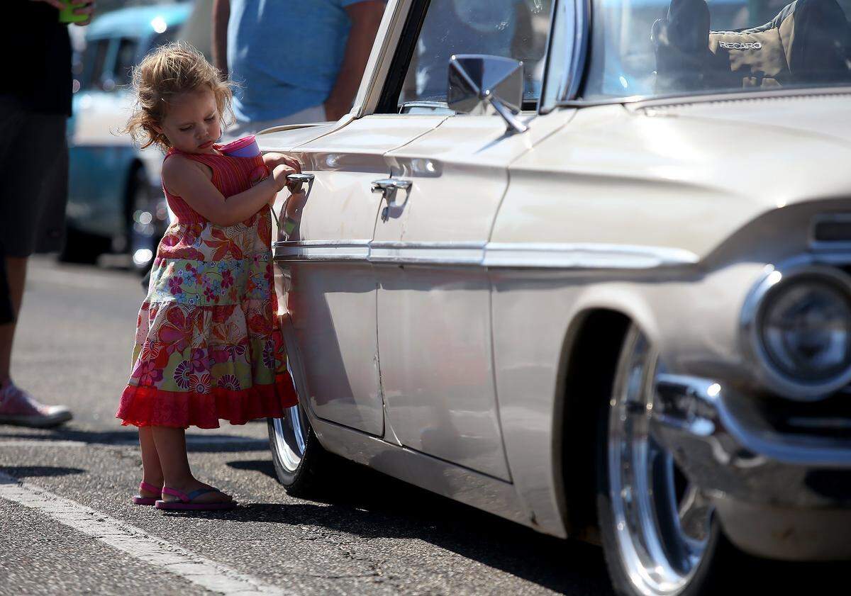 Rose Martin, 3, plays with the door handle of a 1961 Chevrolet Belair during Cruisin’ The Coast on Saturday, October 8, 2016, at the Edgewater Mall.