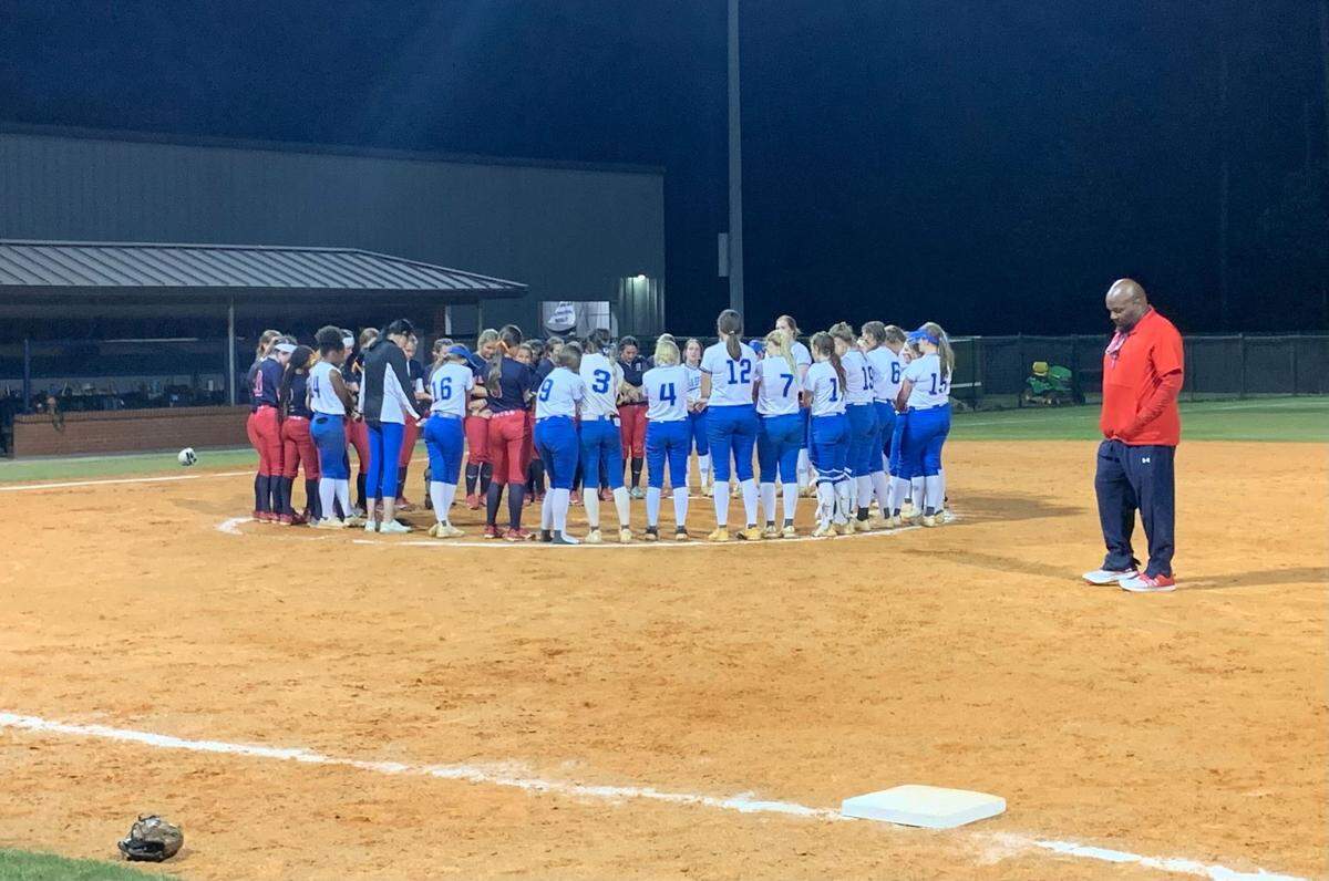 The Hancock and Ocean Springs softball teams join in prayer following a round two playoff game in 2023.