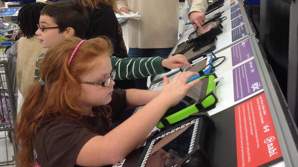 KAREN NELSON/SUN HERALD 
 Debra Holeman, 7, foreground, looks at electronics while program counselor Garret White, background, watches over children in the Visions of Sugarplums program, where each child has $300 to spend on their families and themselves for Christmas.
