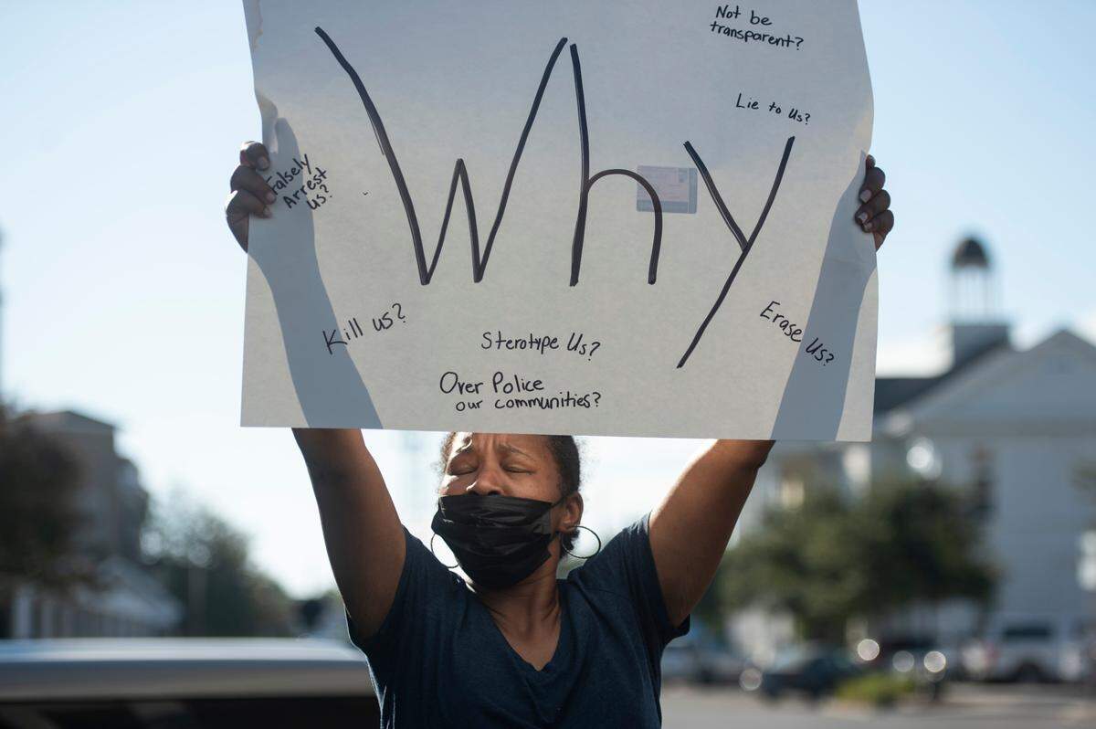 Angela McMillan holds a sign in support of her nephew, Jaheim McMillan, a 15-year-old boy who was shot and killed by police last week, during a protest outside the Gulfport Police Station in Gulfport on Tuesday, Oct. 11, 2022.