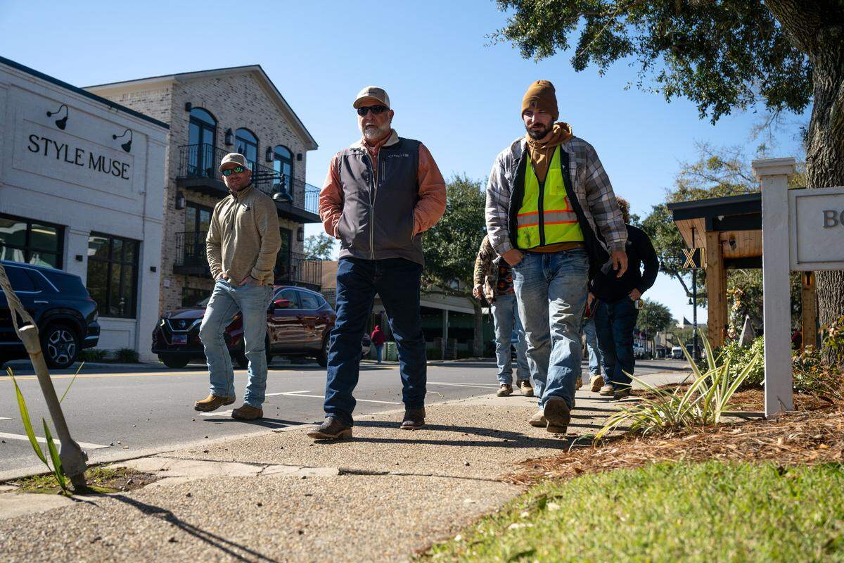 Construction workers walk through downtown Ocean Springs in their winter clothes Monday.