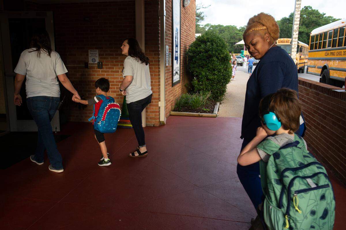 Teachers aids and staff escort kids into the building during the first day of school at Magnolia Park Elementary in Ocean Springs on Friday, Aug. 5, 2022.