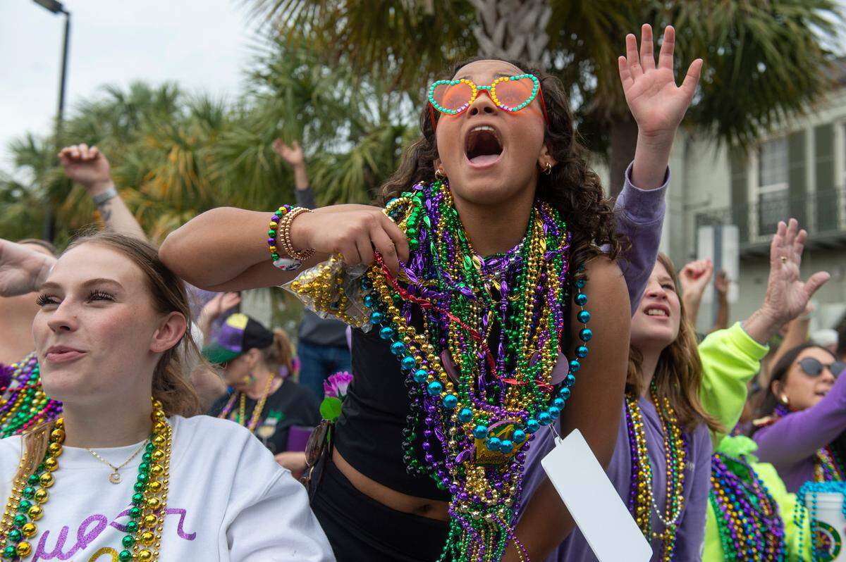 Parade watchers cheer for beads and other throws during the Gulf Coast Carnival Association Mardi Gras parade in Biloxi on Tuesday, March 4, 2025.