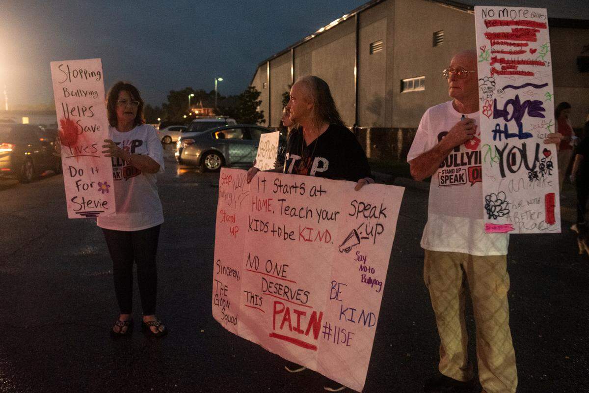 From left, Donna Walker, Ginny English and Steve English hold up signs against bullying outside the D’Iberville High School football game at Warrior Stadium on Friday, Oct. 4, 2024. The Englishes want adults and students to put a stop to bullying after losing their 16-year-old granddaughter to suicide.