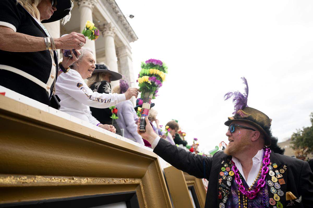 A member of the Ole Biloxi Marching Club hands out flowers to members of the crowd.