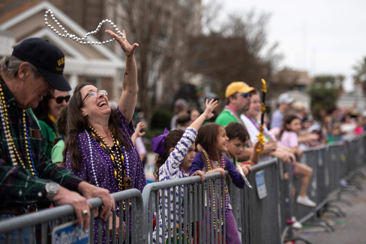 Paradegoers catch beads during the Krewe of Gemini parade in downtown Gulfport on Saturday, Feb. 10, 2024.