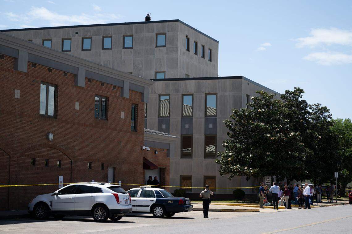 People are escorted out of the Jackson County Courthouse in Pascagoula on Thursday as a police sniper patrols the roof.