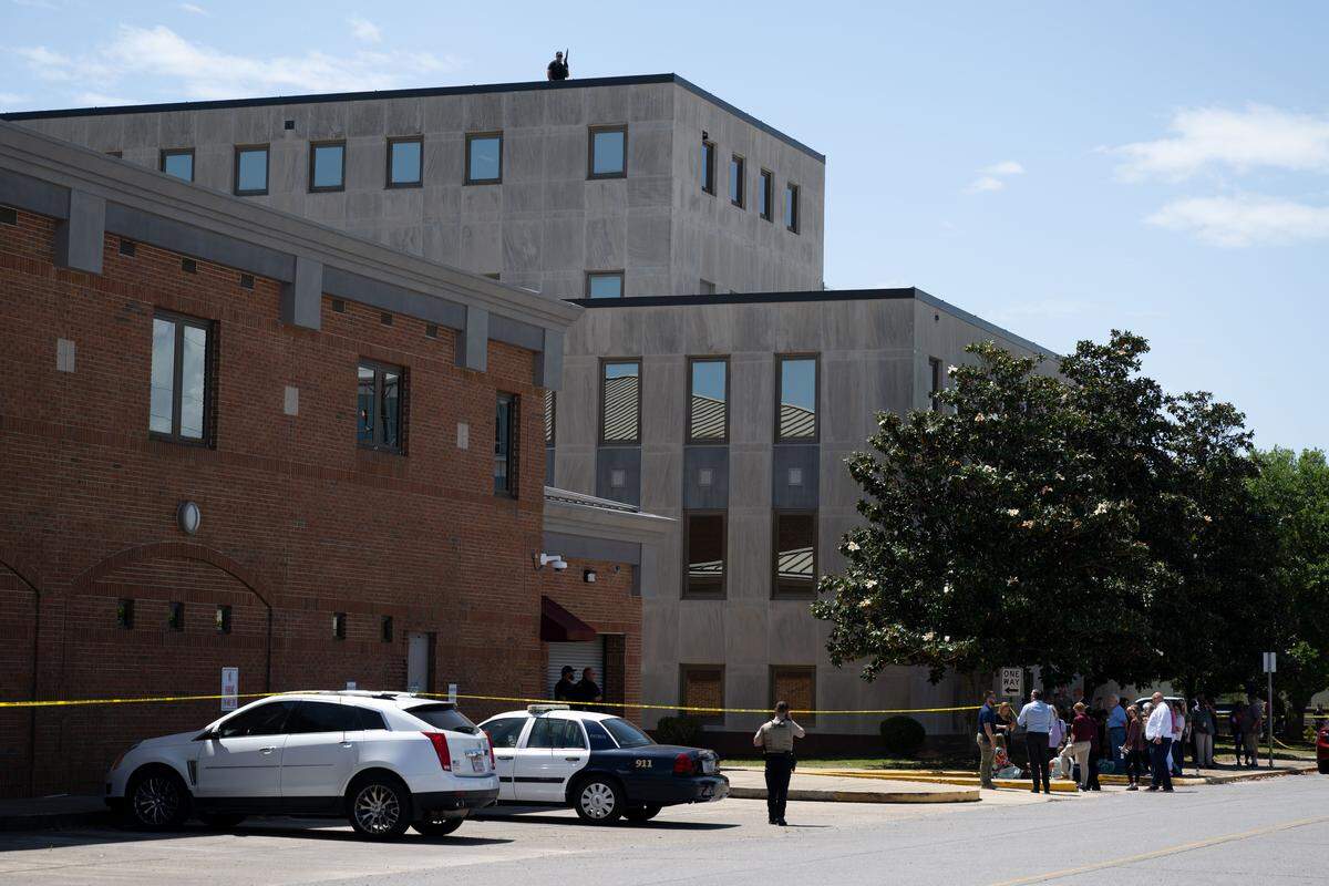 People are escorted out of the Jackson County Courthouse in Pascagoula on Thursday as a police sniper patrols the roof.