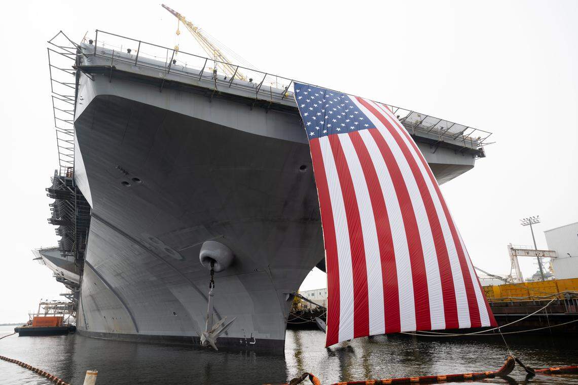 An American flag hangs off the side of LH8 Bougainville, a new amphibious assault ship, during a press conference at Ingalls Shipbuilding on Wednesday, Jan. 7, 2026.